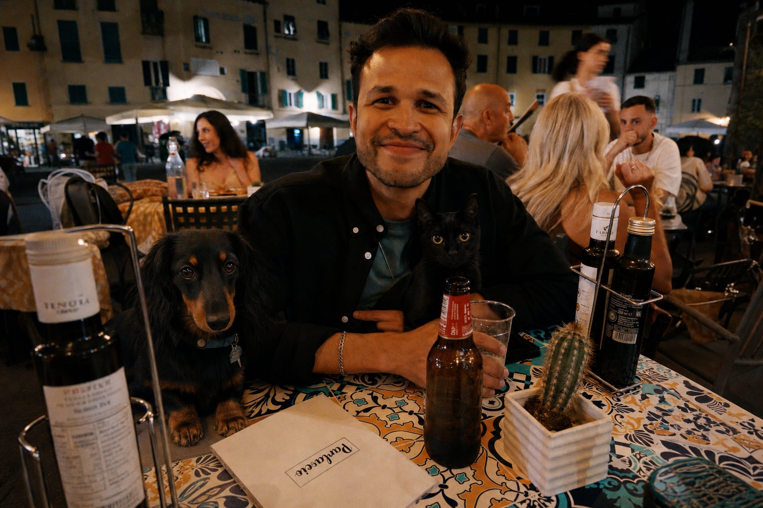 The dog judges the wine; the man smiles anyway.