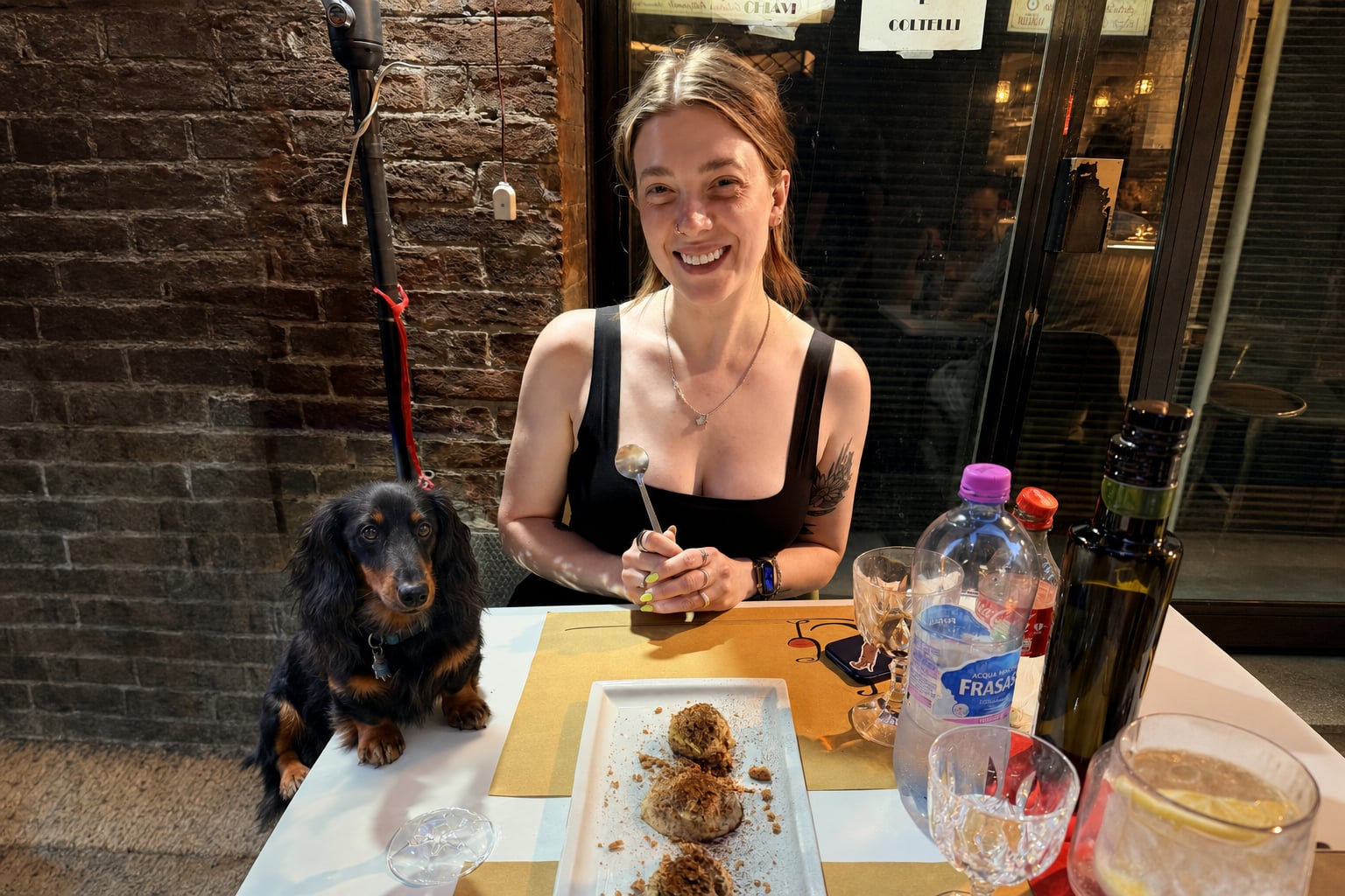 The dog waits for tiramisu; the woman laughs at a future that includes sharing it.